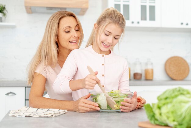 Figlia che produce insalata con sua mamma