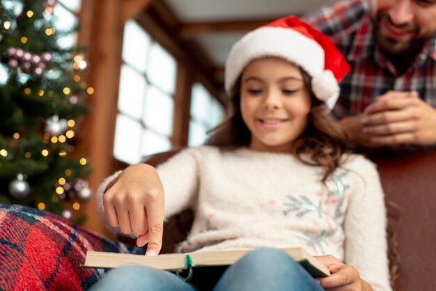 Figlia di angolo basso con il libro sul divano