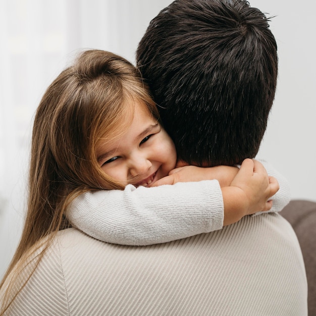 Figlia di smiley che abbraccia suo padre a casa