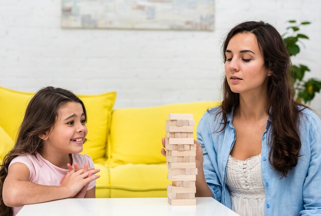 Figlia e madre che giocano un gioco di torre in legno