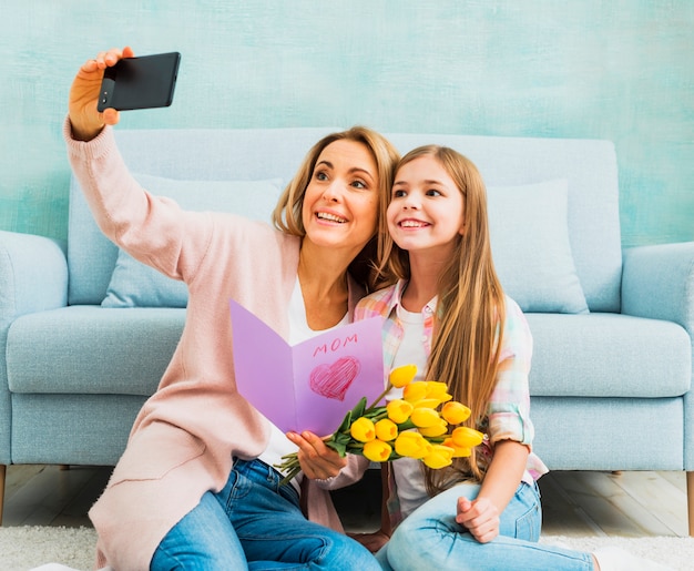 Figlia e madre con regali prendendo selfie