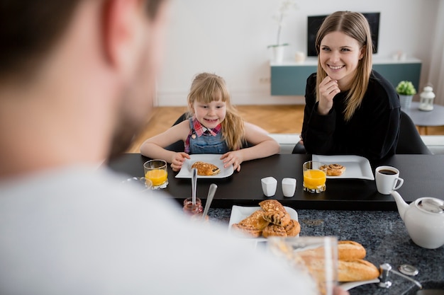 Figlia e mamma guardando il padre durante la colazione