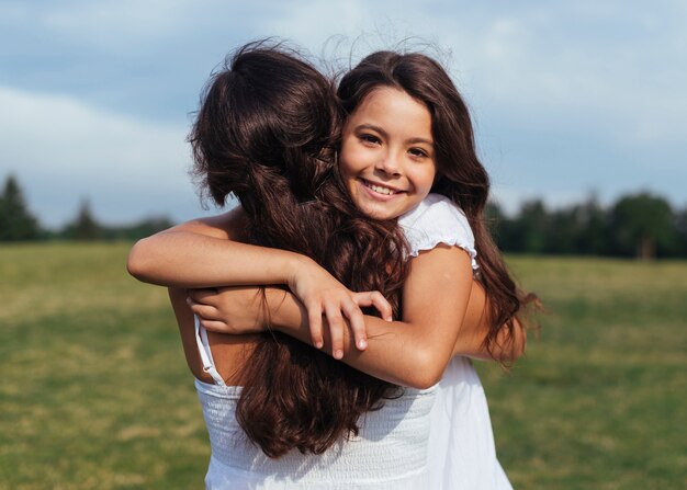 Figlia felice che abbraccia madre all&#39;aperto