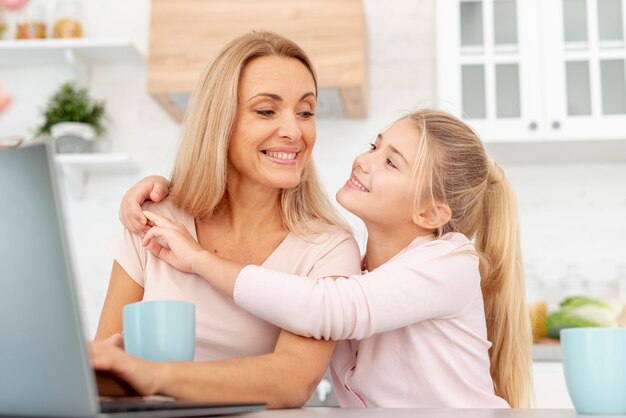 Figlia sorridente che abbraccia sua madre