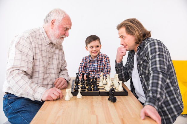 Figlio che sembra padre e nonno che giocano a scacchi