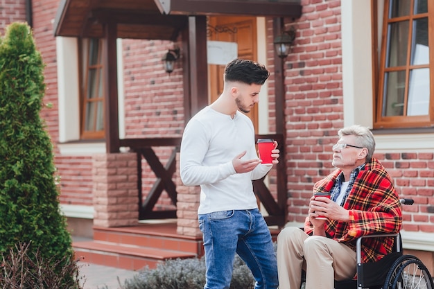 Figlio con suo padre che tiene caffè e parla con papà. Pausa caffè