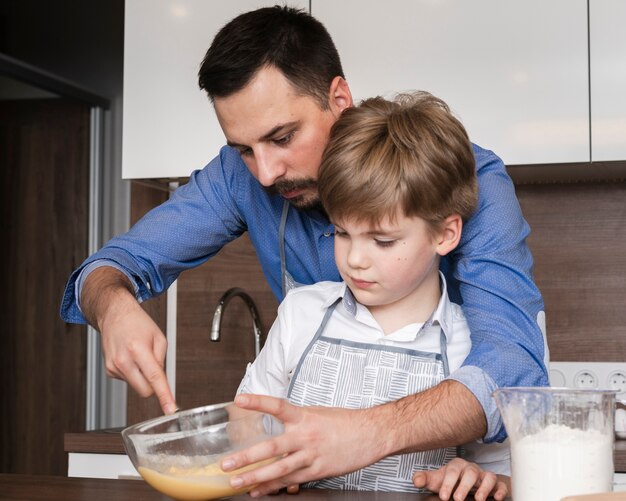 Figlio e padre dell'angolo alto che mescolano le uova