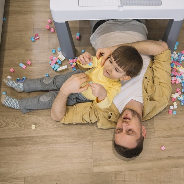 Figlio e padre di alta vista che pongono sul pavimento