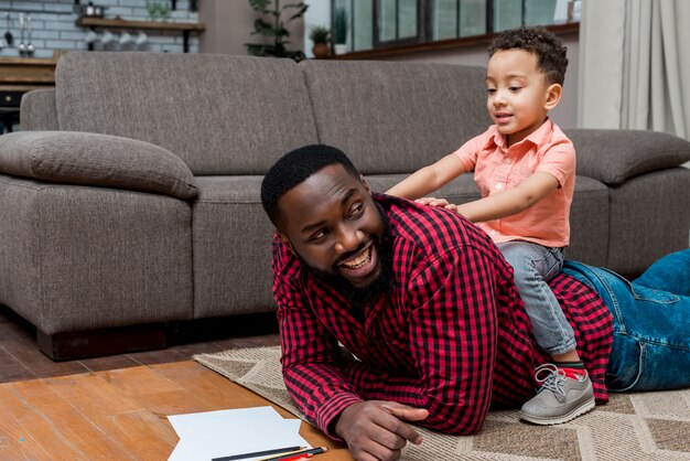 Figlio e padre neri divertendosi sul pavimento