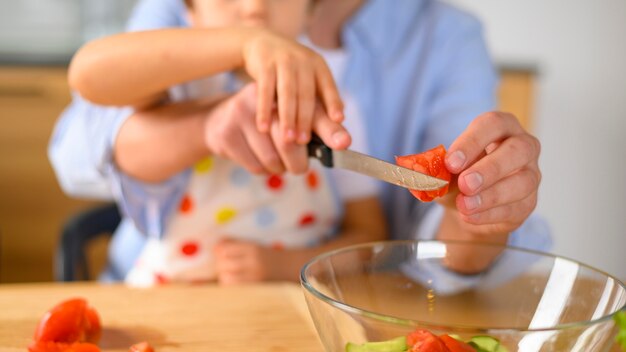 Figlio e papà del primo piano che tagliano un pomodoro