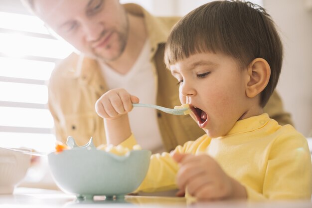 Figlio pronto a prendere un grosso boccone dal suo cibo