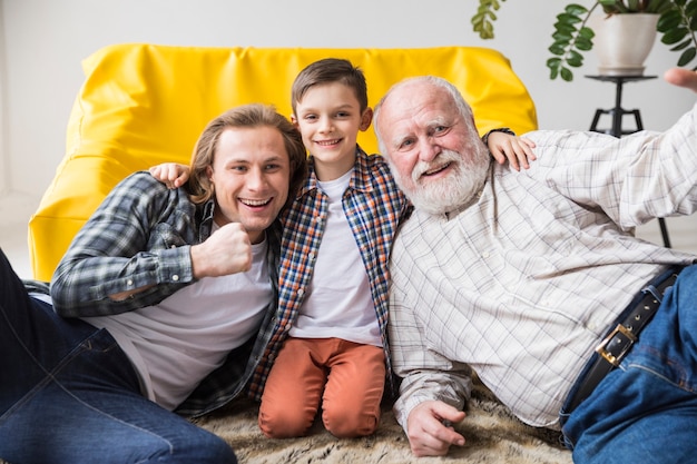 Figlio sveglio allegro che abbraccia papà e nonno