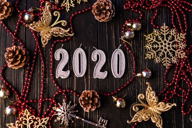 Figura del nuovo anno dalla collana rossa. Rami di abete rosso su tavole di legno, vista dall'alto. Decorazioni natalizie su fondo in legno. Copia spazio