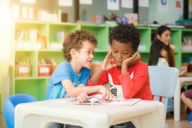 Fila di alunni multietnici elementari che leggono il libro in classe. Immagini di stile d&#39;effetto vintage.