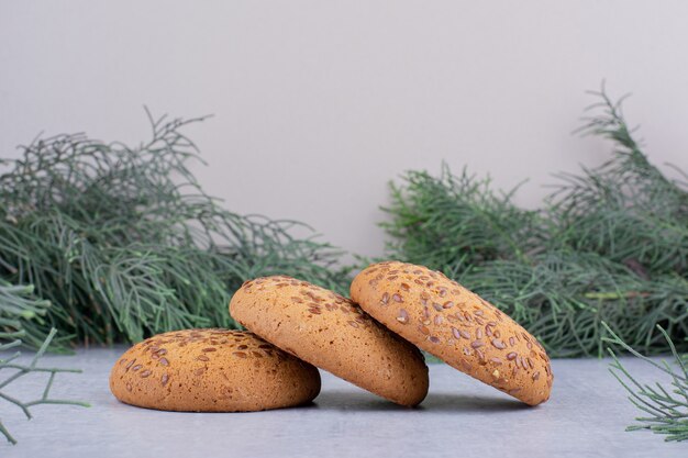 Fila di biscotti circondata da rami di pino su sfondo bianco.