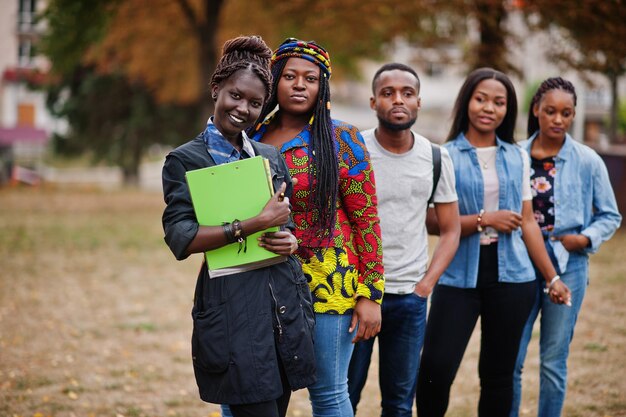 Fila di cinque studenti universitari africani del gruppo che trascorrono del tempo insieme nel campus del cortile dell'università Amici afro neri che studiano il tema dell'istruzione