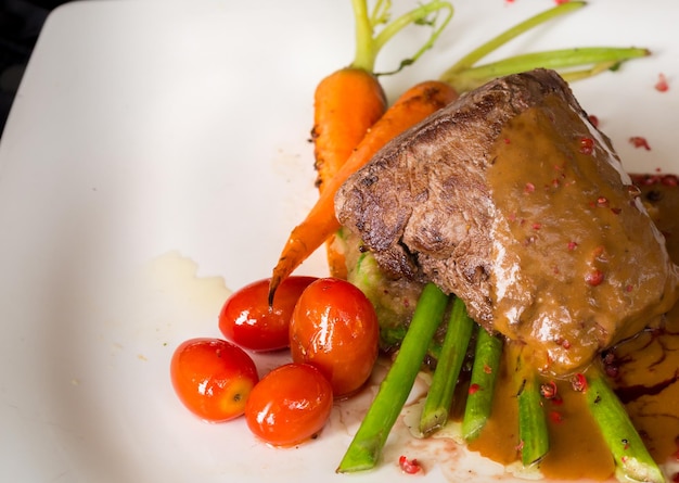 Filetto di manzo alla griglia con asparagi e pomodoro in salsa di vino rosso.