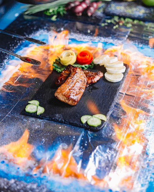 Filetto di pesce grigliato vista laterale con limone e cetriolo su un vassoio