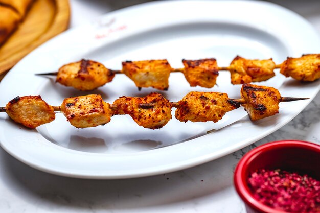 Filetto di pollo alla griglia con spiedini di pollo con sale e pepe su un piatto