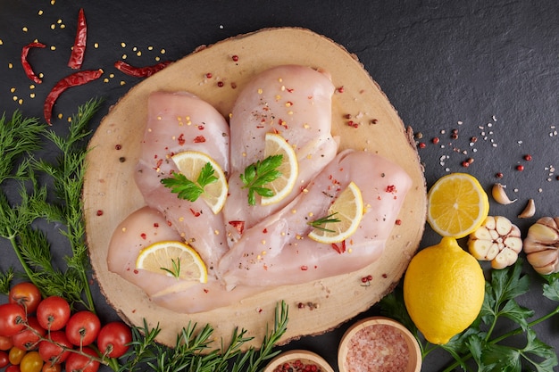 filetto di pollo crudo con aglio, pepe e rosmarino su legno sul tagliere.