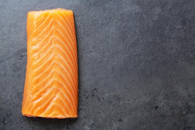 Filetto di salmone crudo su fondo di pietra scura. Avvicinamento