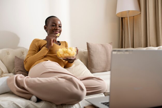 Film di visione della donna del colpo pieno sul computer portatile