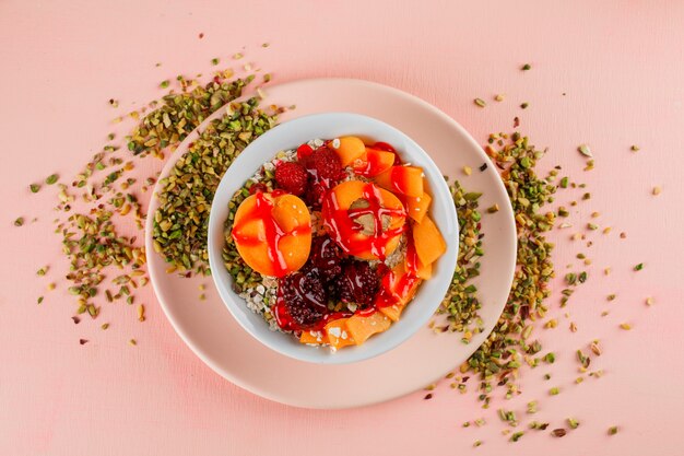 Fiocchi d'avena in una ciotola con pistacchi, albicocche, frutti di bosco, gelatina