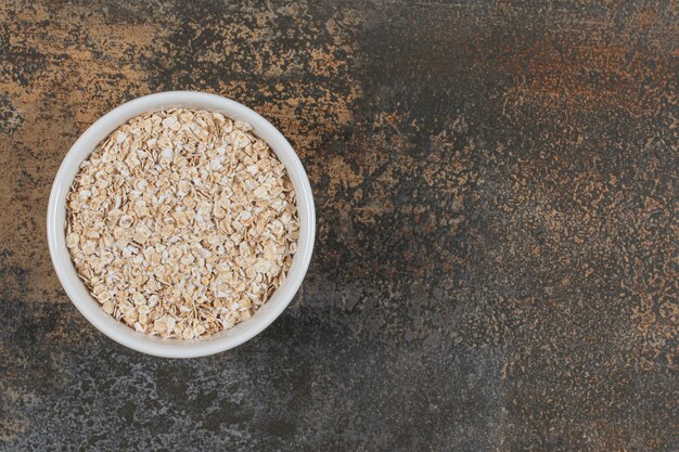 Fiocchi d'avena secchi in una ciotola bianca.