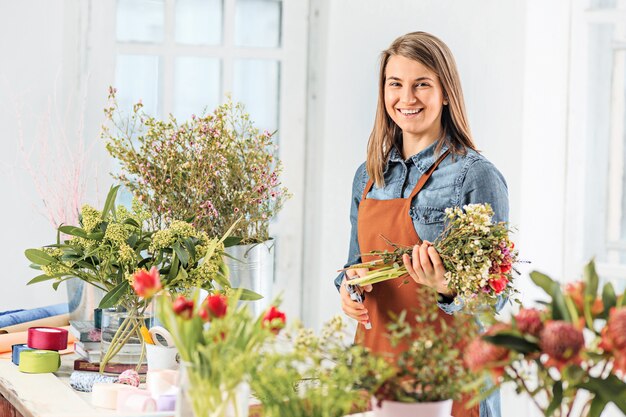 Fioraio al lavoro: la ragazza che fa moda bouquet moderno di fiori diversi