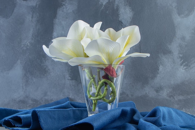 Fiori bianchi freschi in un bicchiere su un pezzo di tessuto, sullo sfondo bianco. Foto di alta qualità