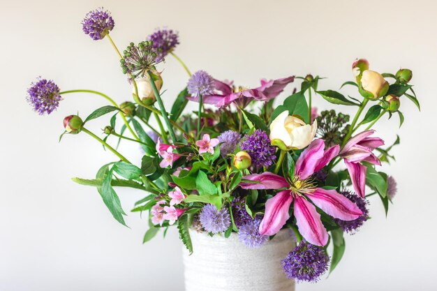 Fiori da un giardino domestico in un vaso su sfondo bianco