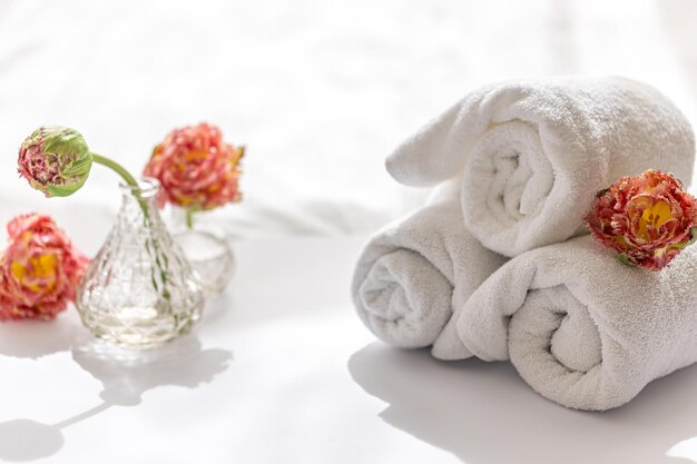 Fiori e asciugamani da bagno in spugna bianchi del primo piano