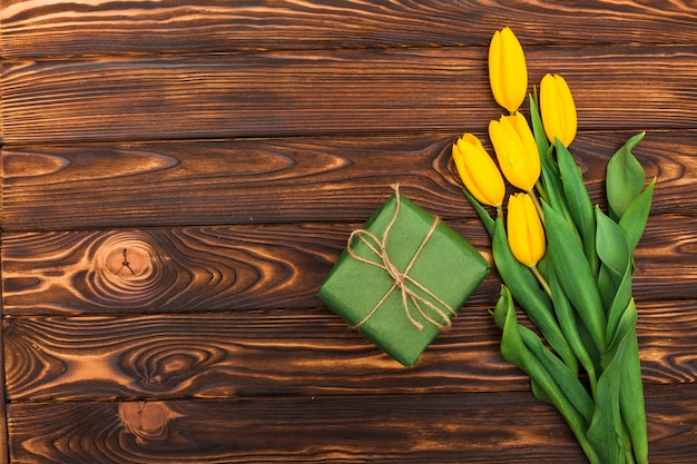 Fiori gialli del tulipano con il contenitore di regalo sulla tavola