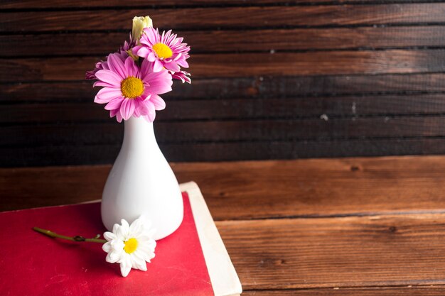 Fiori luminosi in vaso bianco sul libro