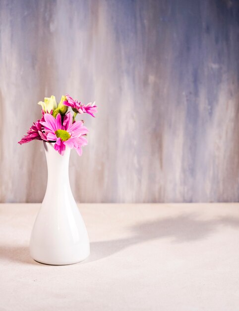 Fiori luminosi in vaso bianco sul tavolo