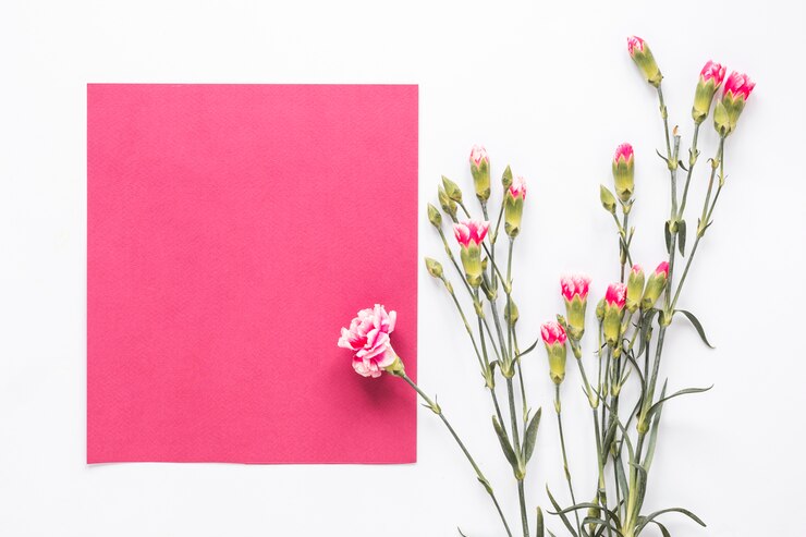 Foto gratuito fiori rosa con carta bianca sul tavolo