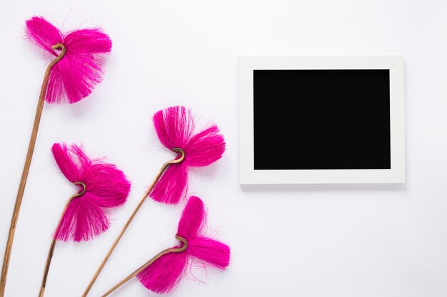 Fiori rosa con cornice vuota sul tavolo