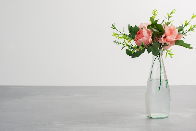 Fiori rosa con foglie verdi in un vaso di vetro.