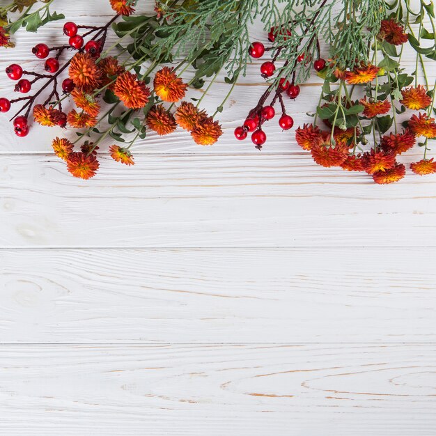 Fiori rossi con bacche sparse sul tavolo di legno