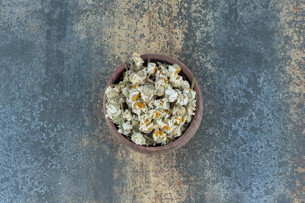 Fiori secchi di camomilla in ciotola di legno.