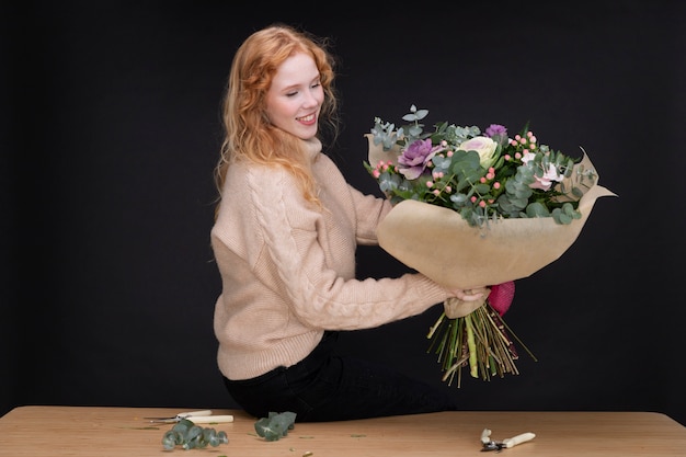 Fiorista a colpo medio che tiene un bouquet