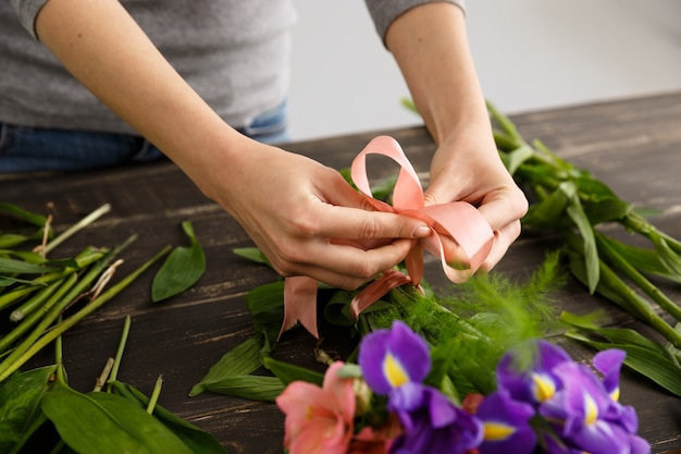 Fiorista che fa i fiori del mazzo, fissa il nastro