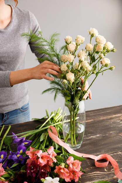 Fiorista che fa i fiori del mazzo in vaso