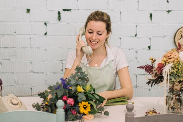 Fiorista con bouquet parlando al telefono