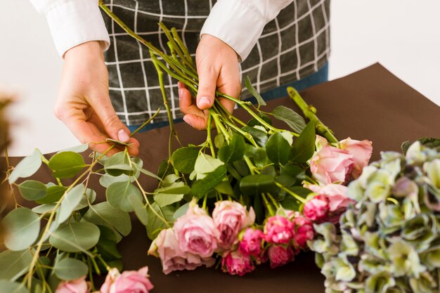 Fiorista del primo piano che sistema le rose rosa