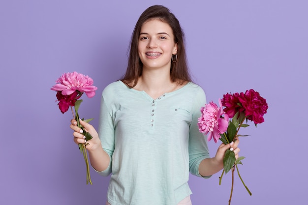 fiorista di giovane donna che fa il mazzo con i fiori, tenendo le peonie in mano