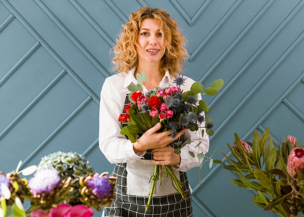 Fiorista di smiley del colpo medio che tiene un mazzo dei fiori