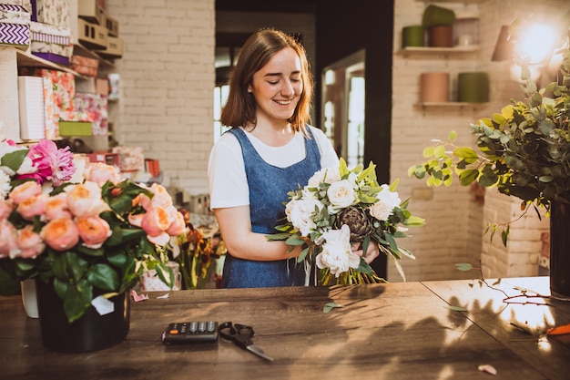 Fiorista donna nel suo negozio floreale prendersi cura dei fiori