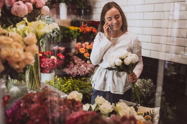 Fiorista donna nel suo negozio floreale prendersi cura dei fiori