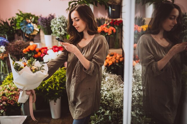 Fiorista donna nel suo negozio floreale prendersi cura dei fiori